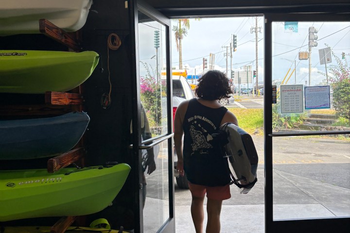 Person exits a building with kayaks on the left and a street scene visible outside.