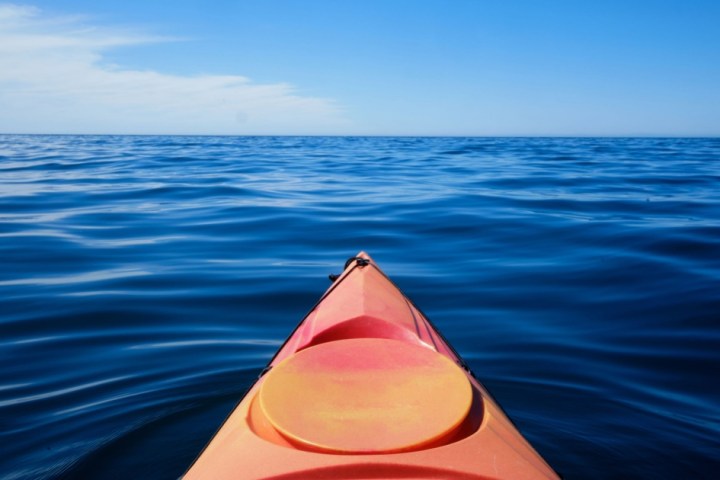 a body of water with an orange umbrella
