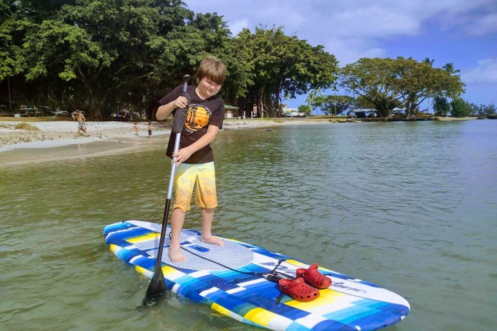 a young boy standing next to a body of water