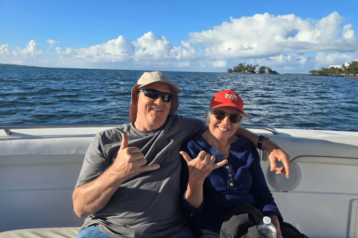 Two people smiling, sitting on a boat with ocean view.
