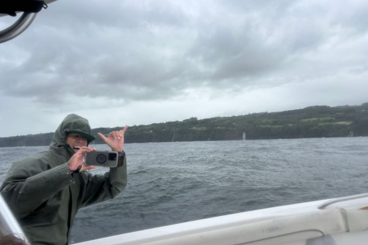 Person on a boat taking a photo in front of a cloudy seascape.
