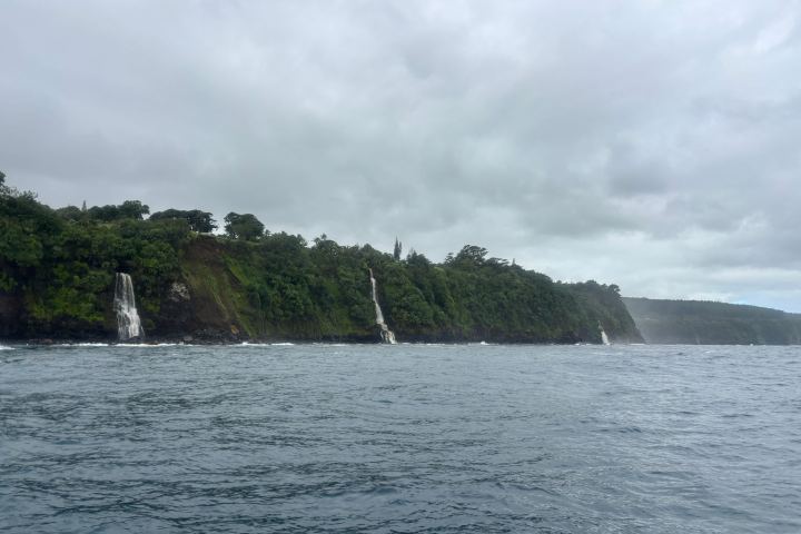 Coastal cliffs with waterfalls under a cloudy sky.
